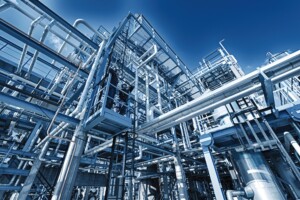 A complex industrial structure with numerous pipes and metal frameworks under a clear blue sky